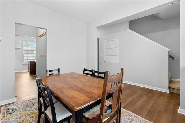 dining room with stairs, dark wood finished floors, and baseboards