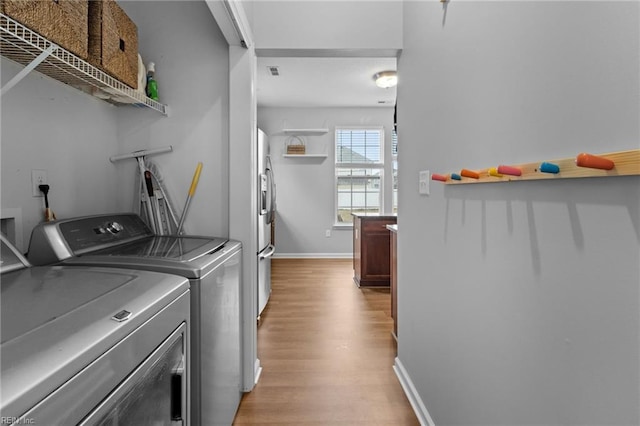 washroom featuring visible vents, light wood-style flooring, washer and dryer, laundry area, and baseboards