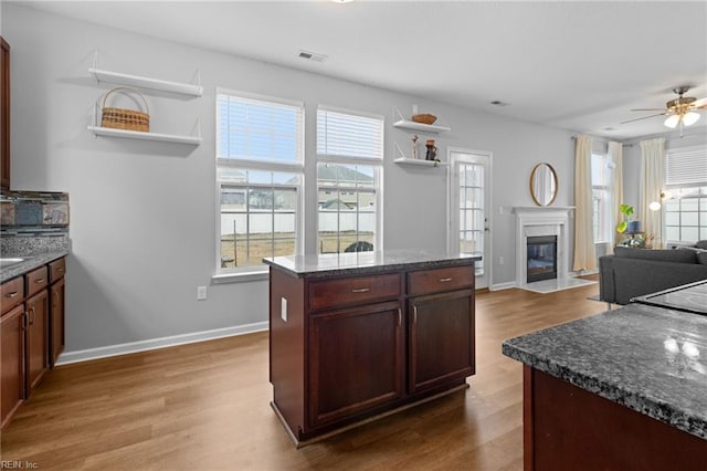 kitchen with a premium fireplace, wood finished floors, visible vents, baseboards, and open shelves