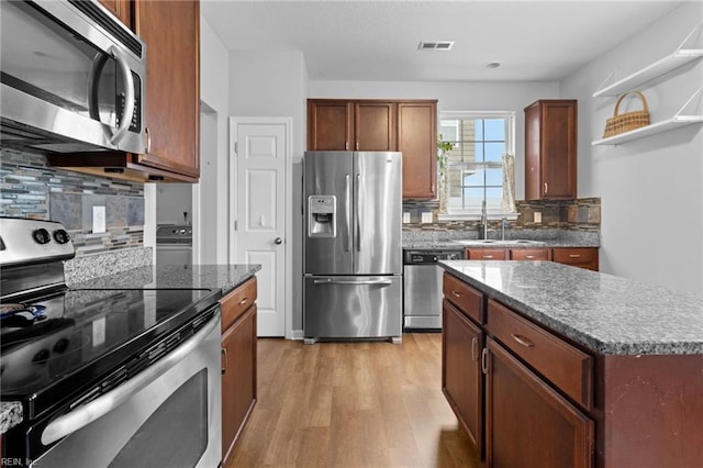 kitchen featuring visible vents, a kitchen island, appliances with stainless steel finishes, light wood-type flooring, and open shelves