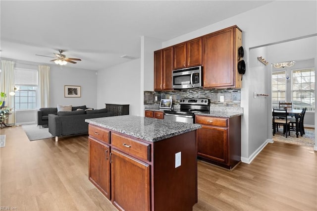 kitchen with stainless steel appliances, a center island, open floor plan, and dark stone countertops