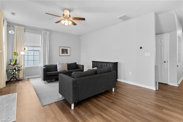 living area featuring visible vents, ceiling fan, baseboards, and wood finished floors