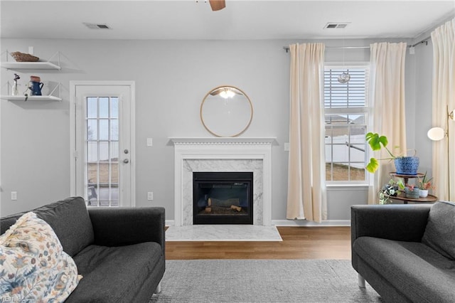 living area with wood finished floors, visible vents, and a healthy amount of sunlight