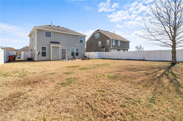 rear view of property featuring a lawn and a fenced backyard