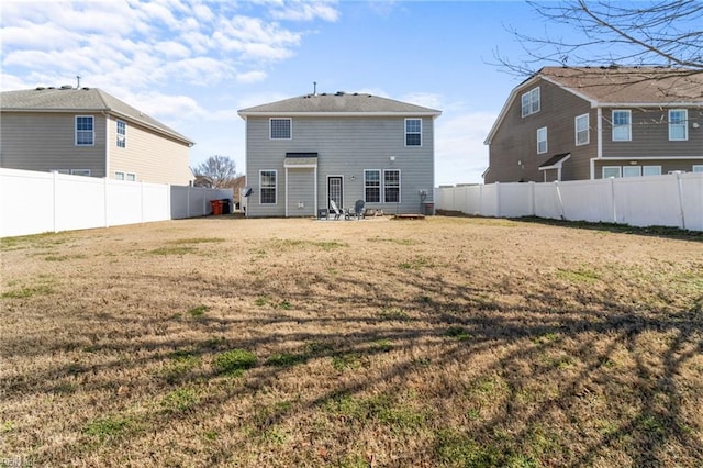 back of house with a fenced backyard and a yard