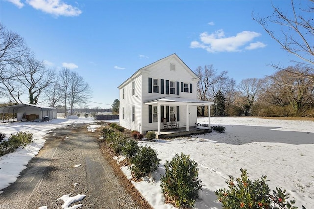 colonial inspired home featuring a carport, a porch, and aphalt driveway