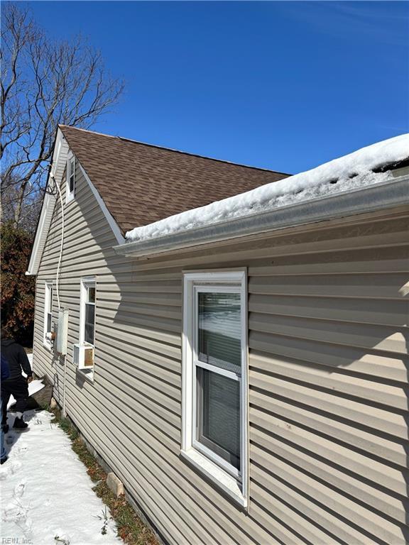 snow covered property featuring roof with shingles