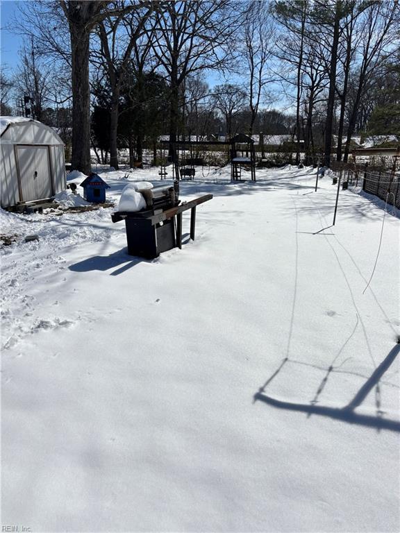 snowy yard featuring a storage shed