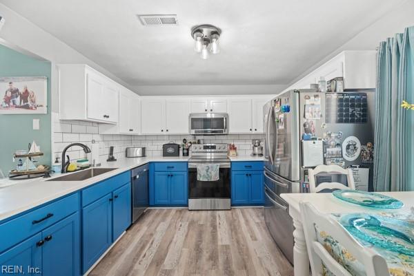 kitchen featuring stainless steel appliances, a sink, visible vents, light countertops, and blue cabinetry