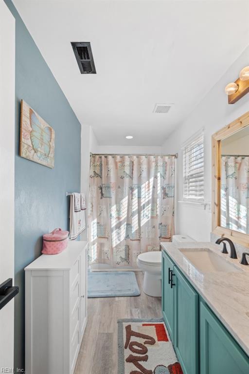 full bath with visible vents, vanity, toilet, and wood finished floors