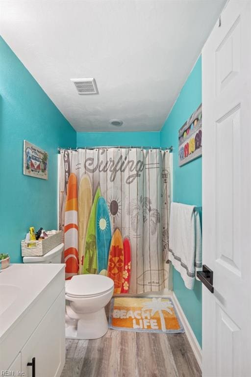 bathroom featuring visible vents, toilet, vanity, wood finished floors, and a shower with curtain