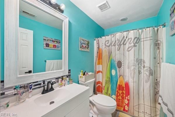 bathroom with toilet, curtained shower, visible vents, and vanity