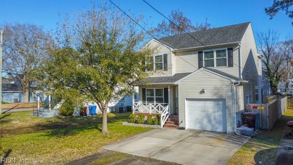 traditional-style house featuring driveway, an attached garage, and a front lawn