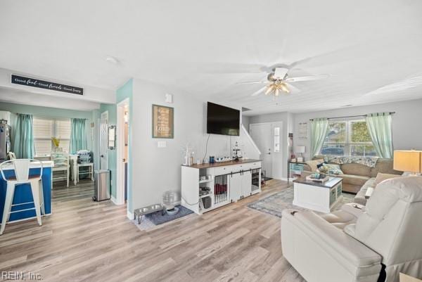 living area with light wood-style floors and a ceiling fan