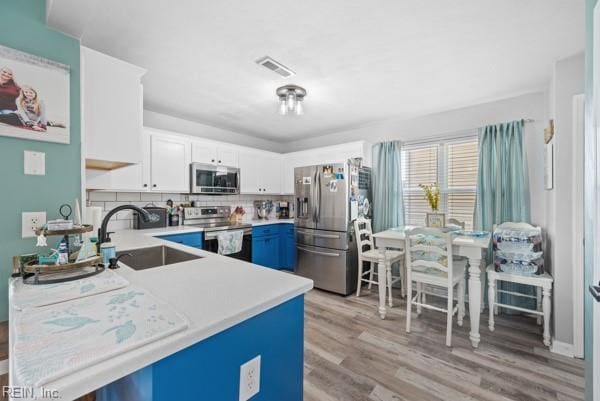 kitchen featuring stainless steel appliances, a sink, visible vents, white cabinets, and light countertops