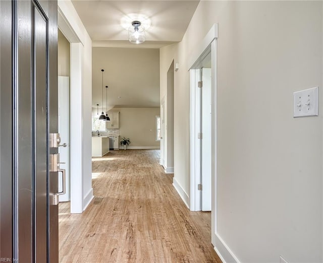 hallway with light wood-type flooring and baseboards