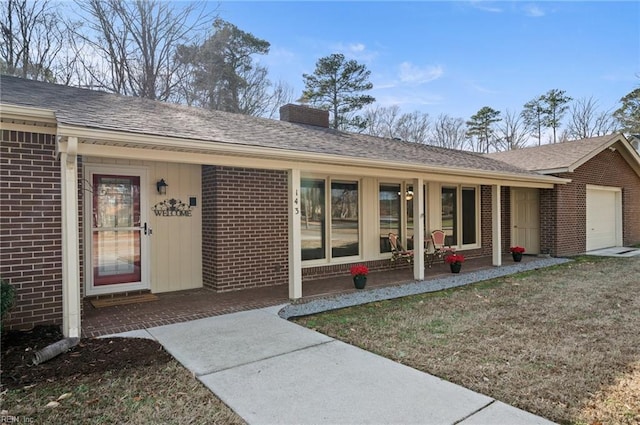 property entrance with a garage, brick siding, a shingled roof, a lawn, and a chimney