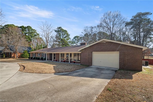 ranch-style house with a garage, concrete driveway, brick siding, and central air condition unit