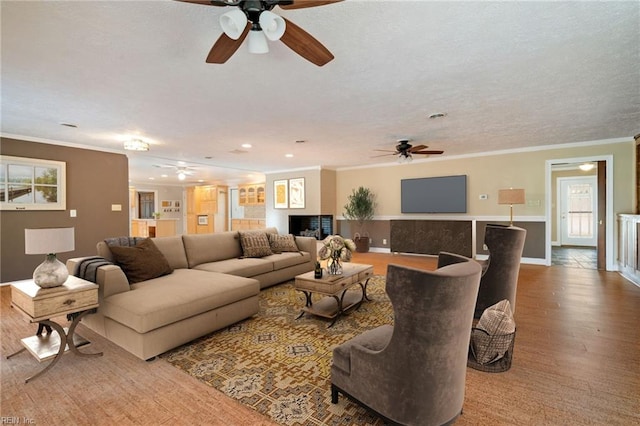 living room featuring baseboards, a textured ceiling, wood finished floors, and crown molding