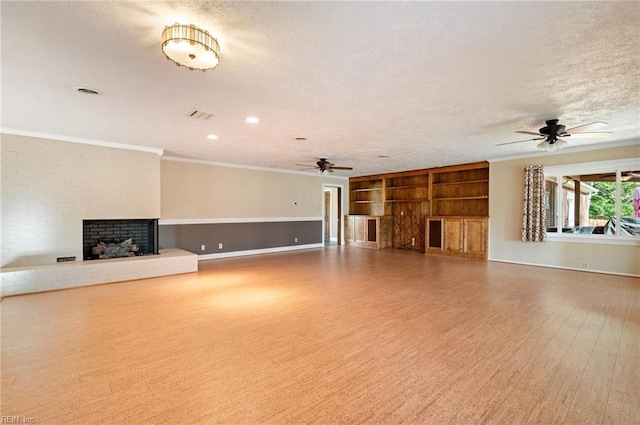 unfurnished living room featuring a textured ceiling, ornamental molding, a brick fireplace, and wood finished floors