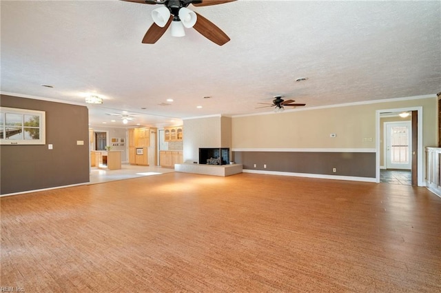 unfurnished living room featuring crown molding, baseboards, a textured ceiling, and a multi sided fireplace