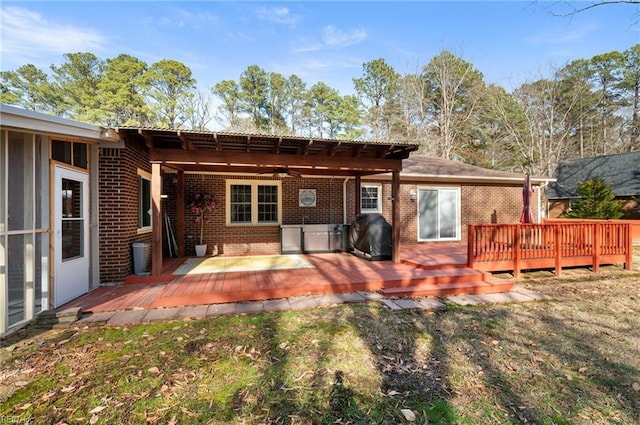 rear view of house featuring brick siding, a yard, and a wooden deck