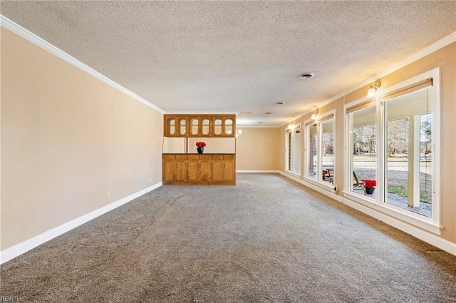 unfurnished living room featuring visible vents, baseboards, carpet, a textured ceiling, and crown molding