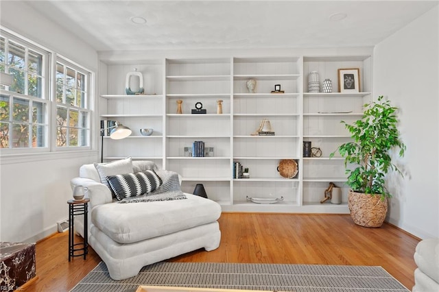 living area featuring baseboards, built in features, and wood finished floors