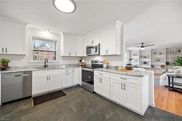 kitchen featuring open floor plan, appliances with stainless steel finishes, a sink, and white cabinetry