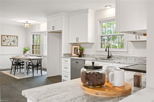 kitchen with white cabinetry, a sink, stainless steel dishwasher, and light stone countertops