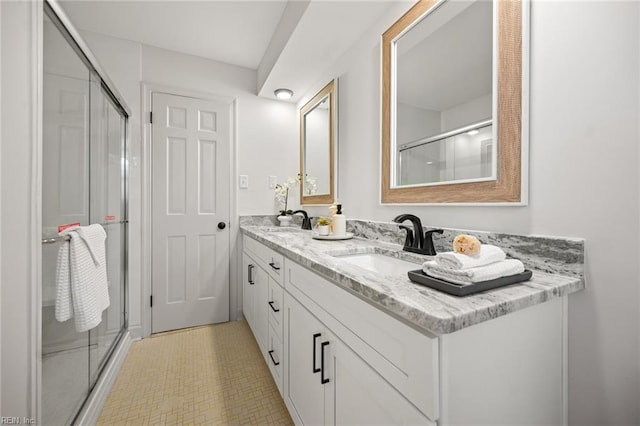 bathroom with a shower with door, a sink, and double vanity