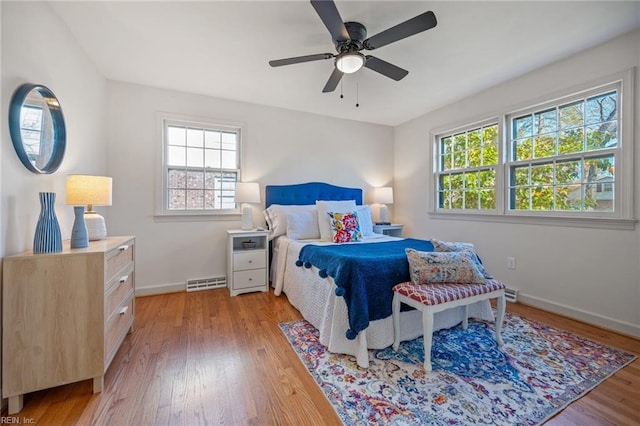 bedroom with light wood-style flooring, visible vents, ceiling fan, and baseboards