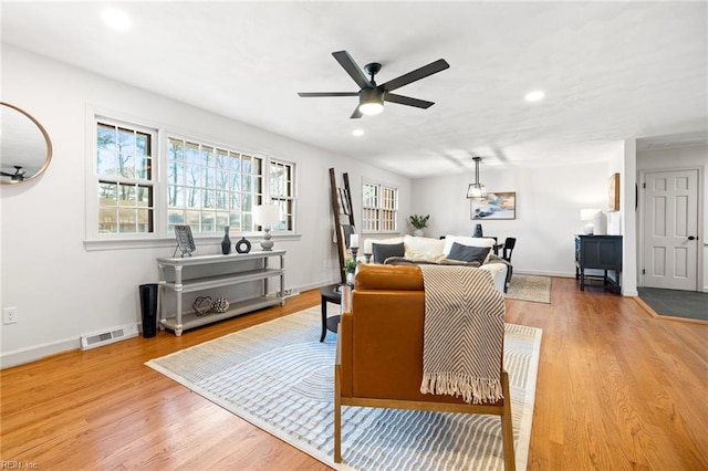 living area with recessed lighting, visible vents, light wood-style flooring, and baseboards