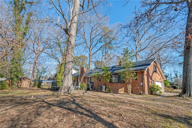 view of front of property featuring a garage, brick siding, and a chimney