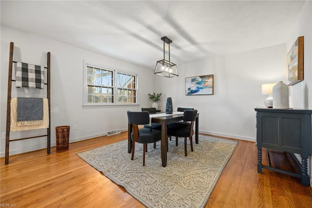 dining room with light wood-style floors, baseboards, and visible vents