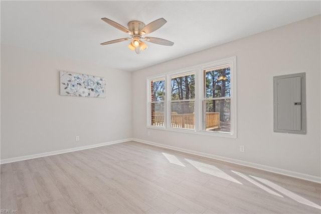 unfurnished room with light wood finished floors, ceiling fan, electric panel, and baseboards