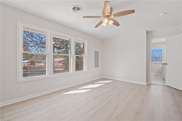 empty room featuring baseboards, electric panel, visible vents, and light wood finished floors