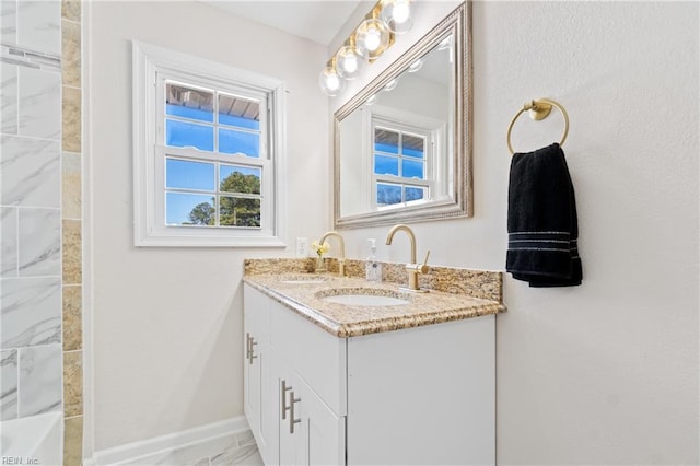 bathroom featuring double vanity, a sink, and baseboards