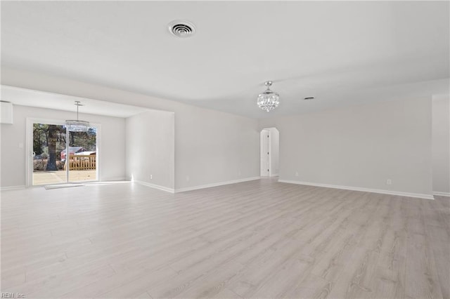 unfurnished room featuring light wood-type flooring, baseboards, visible vents, and arched walkways