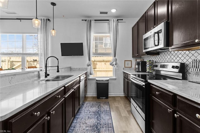 kitchen featuring visible vents, a sink, backsplash, appliances with stainless steel finishes, and light wood finished floors