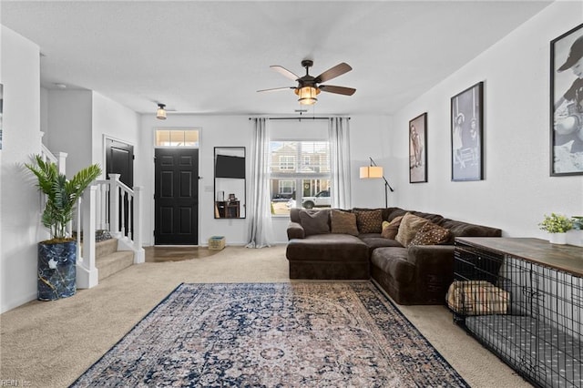 carpeted living room with stairway, a ceiling fan, and baseboards