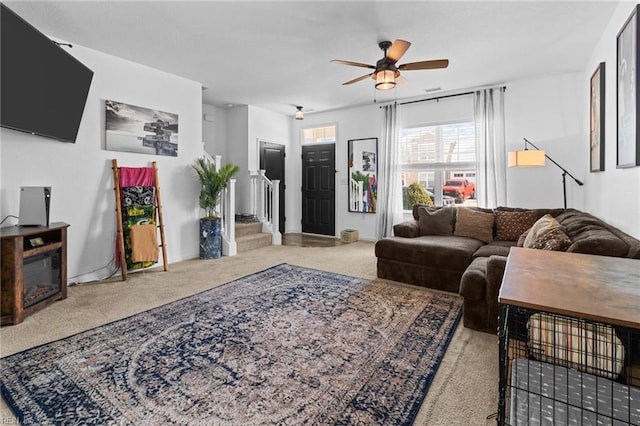 carpeted living area with visible vents, stairs, and a ceiling fan