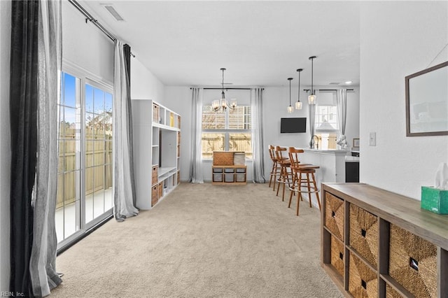 dining room featuring plenty of natural light, visible vents, a chandelier, and light carpet