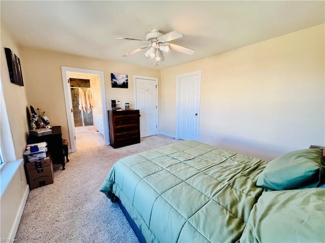 bedroom with a ceiling fan, light carpet, ensuite bath, and baseboards