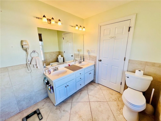 full bath with a sink, tile walls, and toilet