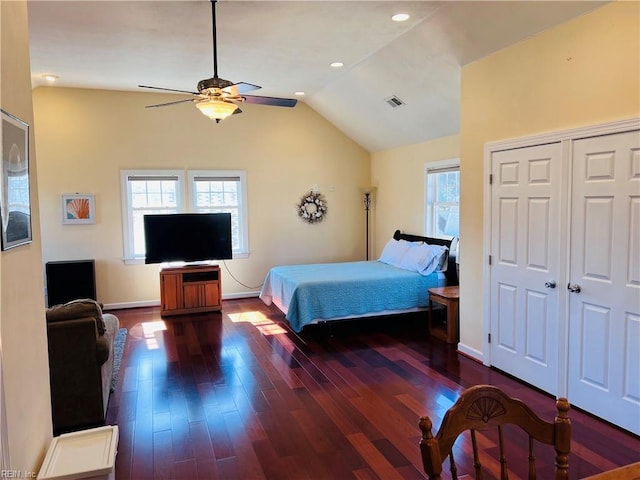 bedroom with vaulted ceiling, wood finished floors, visible vents, and baseboards