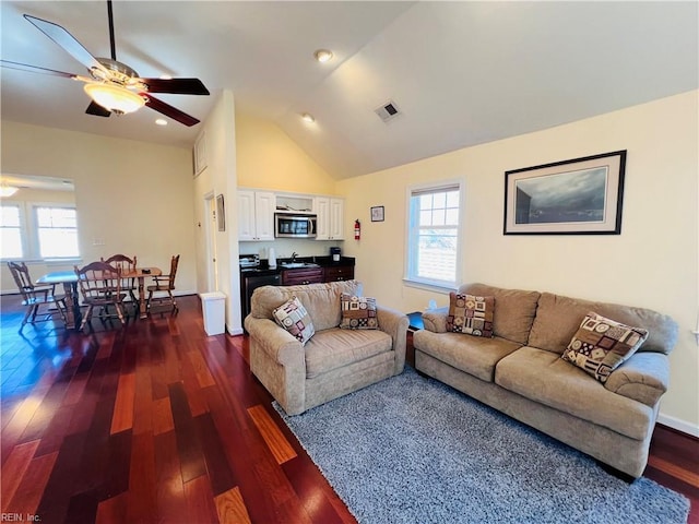 living area featuring dark wood-style flooring, a healthy amount of sunlight, vaulted ceiling, and ceiling fan