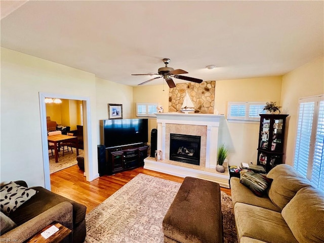 living room featuring a ceiling fan, a tile fireplace, and wood finished floors