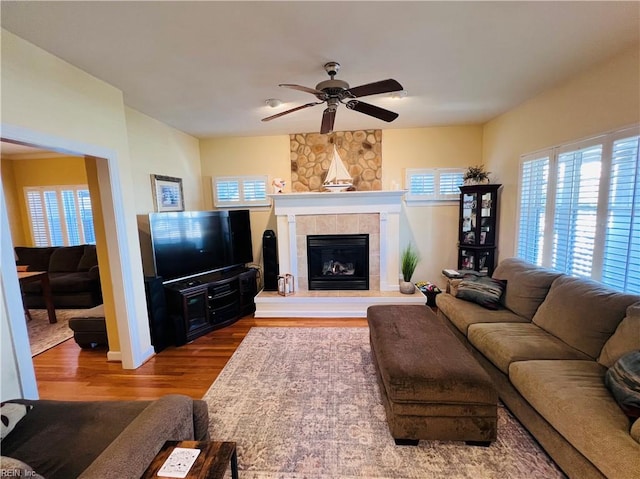 living room featuring ceiling fan, a fireplace, and wood finished floors