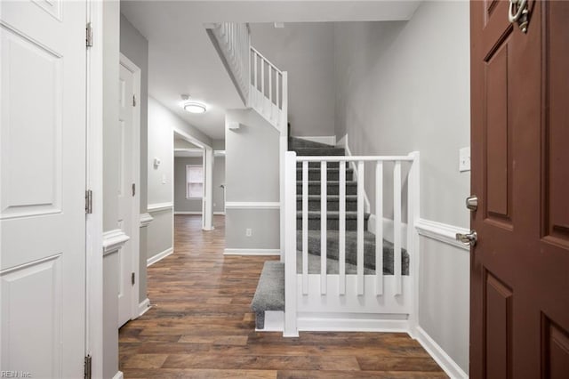 foyer entrance with dark wood-style floors, stairs, and baseboards